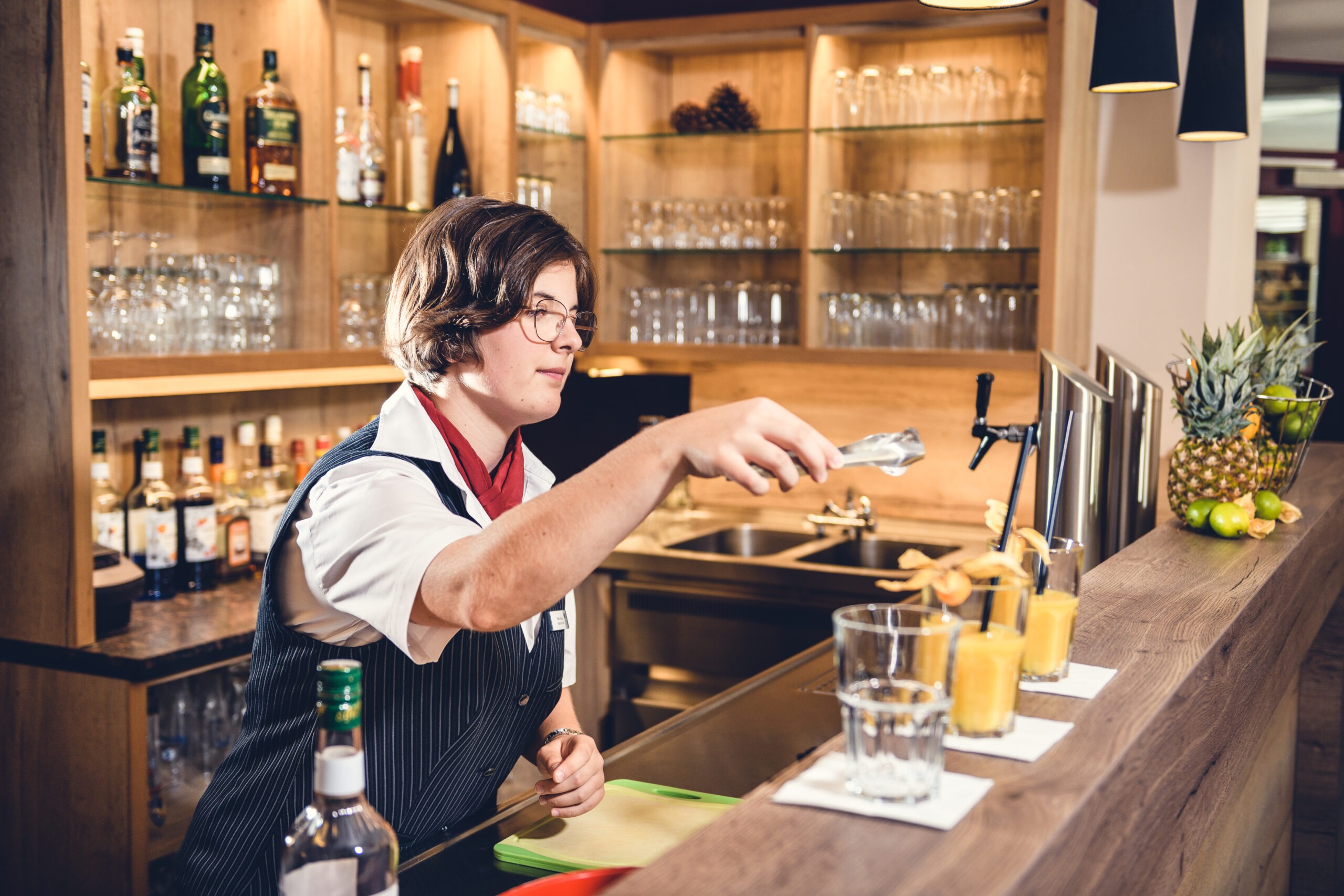 Azubine bereitet Cocktails am Tresen zu